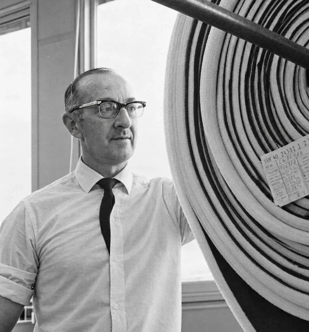 Gösta Fajersson i skjorta och slips bredvid en stor rulle tyg